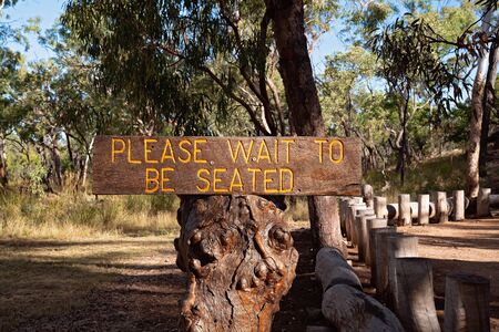 Please wait to be seated sign on an old tree trunk at an Australian bush breakfastの写真素材