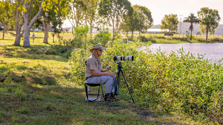 Mackay, Queensland, Australia - January 2021: Male retiree photographer taking photos of birds on a...