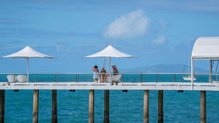 Airlie Beach, Queensland, Australia - February 2021: Female friends relaxing under an umbrella on a jetty over the water on a bright sunny dayのeditorial素材