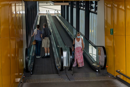 Brisbane Airport, Queensland, Australia - March 2021: People with masks traveling on escalators...