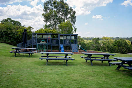 Brisbane, Queensland, Australia - March 2021: Outdoor wooden tables and children's playground on lawn with a scenic viewのeditorial素材