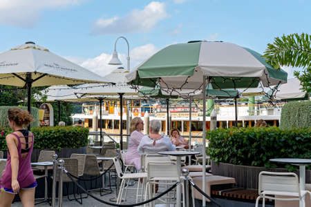 Brisbane, Queensland, Australia - March 2021: Women dining at an outdoor restaurant by the river with a show boat cruise in the backgroundのeditorial素材