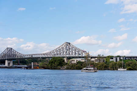 Brisbane, Queensland, Australia - March 2021: Boats cruising the river in front of bridge with long spanのeditorial素材