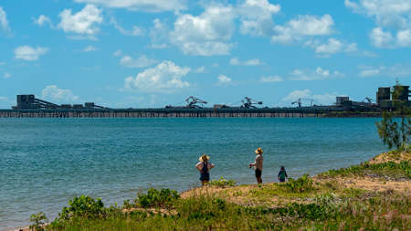 Mackay, Queensland, Australia - March 2021: Dalrymple Bay Coal terminal loading facility on the coast with people fishing on the beachのeditorial素材