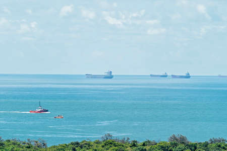 Mackay, Queensland, Australia - March 2021: Container ships anchored on the horizon waiting to load coal at terminal with a tug boat in the foregroundのeditorial素材
