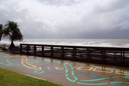A colorfully painted public footpath beside steps down to the beach on a wet and rainy dayの写真素材