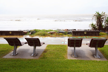 Rain coming in over the ocean in front of timber lounge chairs on a wet and cloudy day
