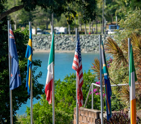 Airlie Beach, Queensland, Australia - April 2021: Multiple country flags flying at a tourist resort overlooking the beachのeditorial素材