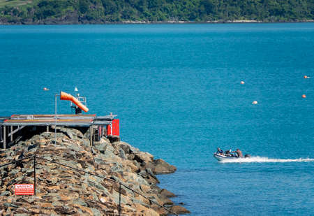 Airlie Beach, Queensland, Australia - April 2021: An inflatable boat speeding past a helicopter landing pad on the oceanのeditorial素材