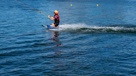 Mackay, Queensland, Australia - April 2021: A young girl wearing a safety helmet and life jacket enjoying a ride on a knee board at a cable parkのeditorial素材