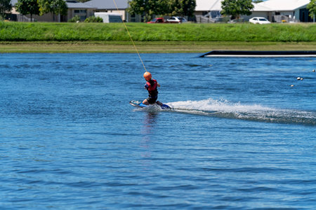 Mackay, Queensland, Australia - April 2021: A young girl wearing a safety helmet and life jacket enjoying a ride on a knee board at a cable parkのeditorial素材