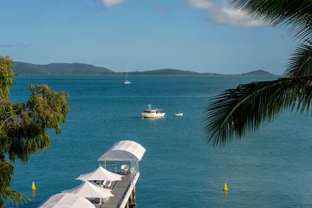 Airlie Beach, Queensland, Australia - April 2021: A pier covered with white sails and umbrellas stretching out to sea with boats in the distanceのeditorial素材
