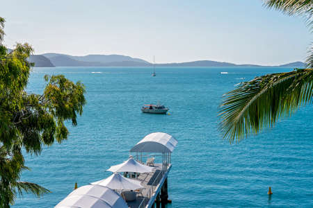 Airlie Beach, Queensland, Australia - April 2021: A pier covered with white sails and umbrellas stretching out to sea with boats in the distanceのeditorial素材