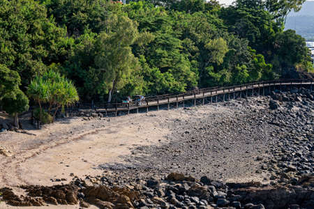 Airlie Beach, Queensland, Australia - April 2021: People riding bicycles with covered wagons for children along a walkway by the beachのeditorial素材