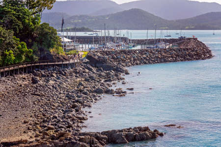 Airlie Beach, Queensland, Australia - April 2021: People on walking track along the ocean from the marina on a rocky shorelineのeditorial素材