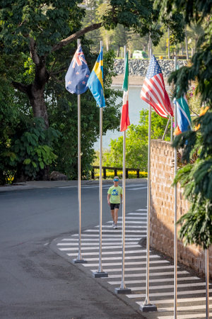 Airlie Beach, Queensland, Australia - April 2021: Person walking along footpath lined with country flagsのeditorial素材