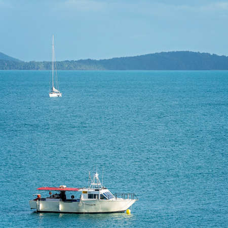 Airlie Beach, Queensland, Australia - April 2021: Old fishing boat and luxury yacht anchored in sheltered bay of water for the dayのeditorial素材