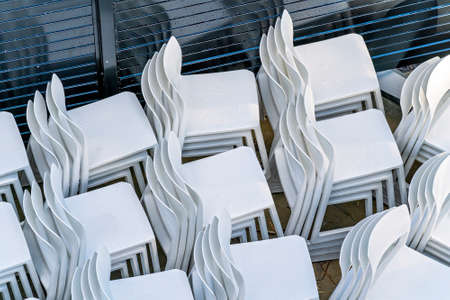 White plastic chairs stacked in a yard outdoor at a resort hotel for later useの写真素材