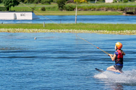 Mackay, Queensland, Australia - April 2021: A young girl wearing a safety helmet and life jacket enjoying a ride on a knee board at a cable parkのeditorial素材