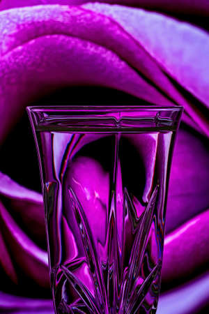 Refraction of a background closeup of a pink rose reflected in the etched crystal foreground glassの写真素材