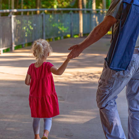Mackay, Queensland, Australia - June 2021: Young girl holding her grandfather's hand as she goes for a walkのeditorial素材