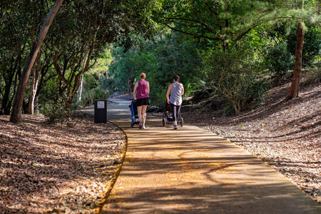 Mackay, Queensland, Australia - June 2021: Two mothers pushing prams with their children as they...