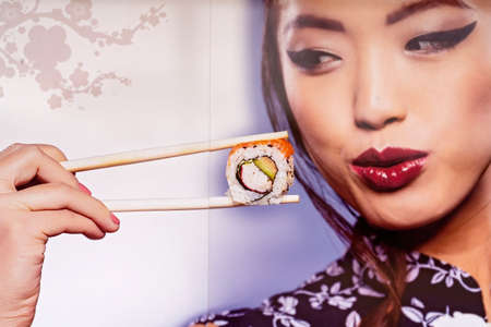 Mackay, Queensland, Australia - June 2021: Advertisement for sushi, girl using chopsticks to admire the foodのeditorial素材