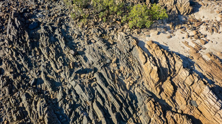 Close up of the texture of rocks on a stoney coastal beach at low tide overhead aerial view