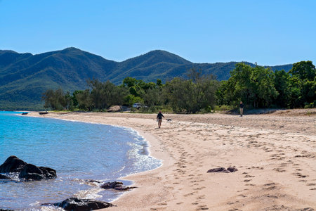 Cape Gloucester, Queensland, Australia - June 2021: Man walking his dog on the beach while a senior male stands nearby flying his droneのeditorial素材