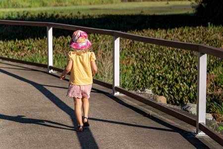 Mackay, Queensland, Australia - June 2021: Little girl walking on her along a footpath beside a pond filled with water liliesのeditorial素材
