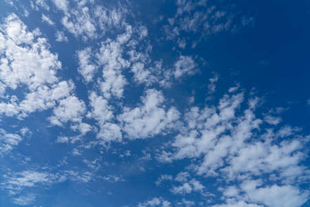 Clouds spread across a deep blue sky on a bright sunny dayの写真素材