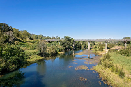 Aerial landscape of a bridge across a rural creek with banks covered in bushland.