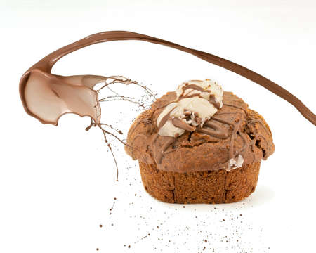 A chocolate muffin with icing and a swirl of chocolate splash on white backgroundの写真素材