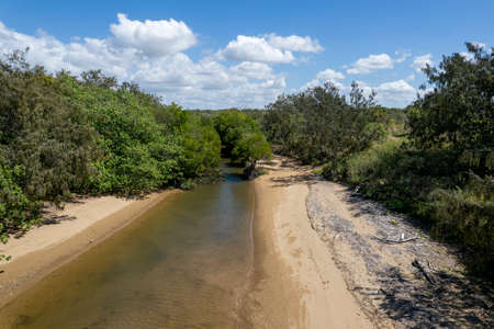Flight by a drone up a creek on the incoming tide in a bushland settingの写真素材