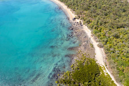 Aerial landscape from a drone flying along the coastline towards an uninhabited sandy beachの写真素材