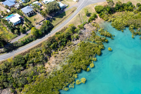 Aerial as drone comes into land on the banks of a coastal bay with blue water and mangrove...