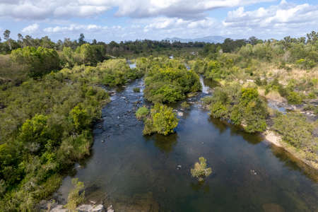 Aerial landscape pattern of a shallow riverbed with water flowing between bushland and rocksの写真素材