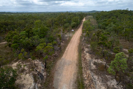 Dirt track leading through bushland into the distance with a danger signの写真素材