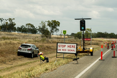 Bruce Highway Mackay to Townsville, Queensland, Australia - November 2021: Stop here on red signal signage watched over by traffic controller during roadworksのeditorial素材