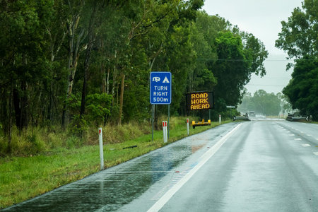 Turn right for camping and road work ahead signs on highway on wet rainy day