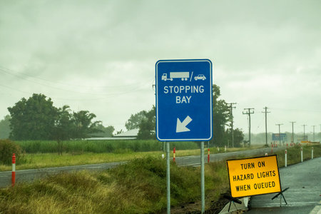 Trucks and cars stopping bay with arrow signage and warning to turn on hazard lights when queued,...