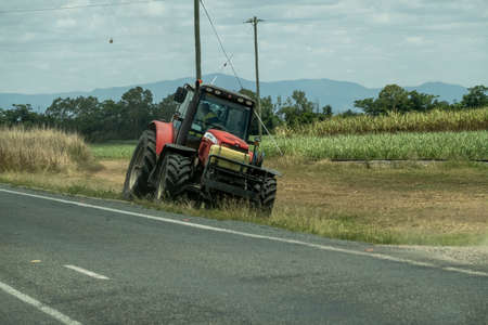 Bruce Highway Townsville to Mackay, Queensland, Australia - November 2021: Man driving tractor mowing grass on side of roadのeditorial素材