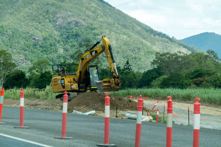 Bruce Highway, Townsville to Mackay, Queensland, Australia - November 2021: Heavy machine scooping soil on road construction work siteのeditorial素材