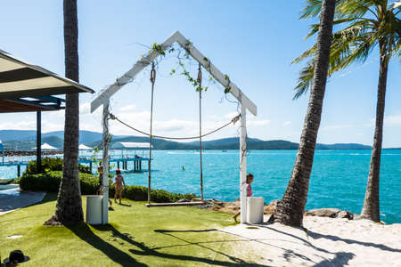 Airlie Beach, Queensland, Australia - December 2021: Children playing around a rope swing on the beachfront of a luxury resort hotel on a hot summer dayのeditorial素材