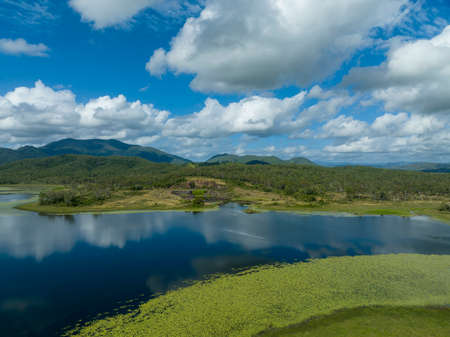 Drone aerial of a quarry on the banks of a dam filled with aquatic plants and cloud reflections on a calm day. Kinchant Dam, Australia.の写真素材