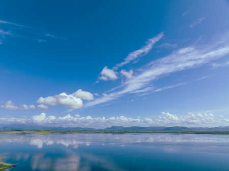Clouds mirrored in the calm water of a rural dam in Australia on a hot summer day.の写真素材