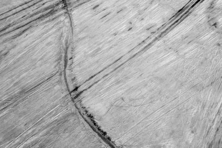 An abstract pattern of vehicle tyre tracks running over salt flats. Drone overhead aerial view of texture in the fine-grained sediment.の写真素材