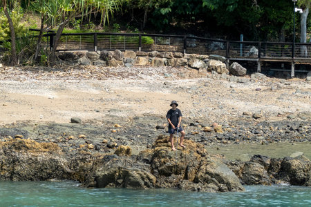 Airlie Beach, Whitsundays, Queensland, Australia - April 2022: A young man fishing with a rod and...