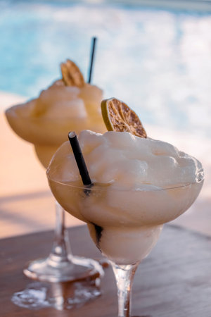Two frozen margaritas with straws and dried fruit to enjoy poolside on a hot tropical day.の写真素材