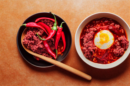 Bowls of hot chili peppers with ground beef, onion, tomato and red kidney beans, topped with an egg. Photo realism illustration.の写真素材